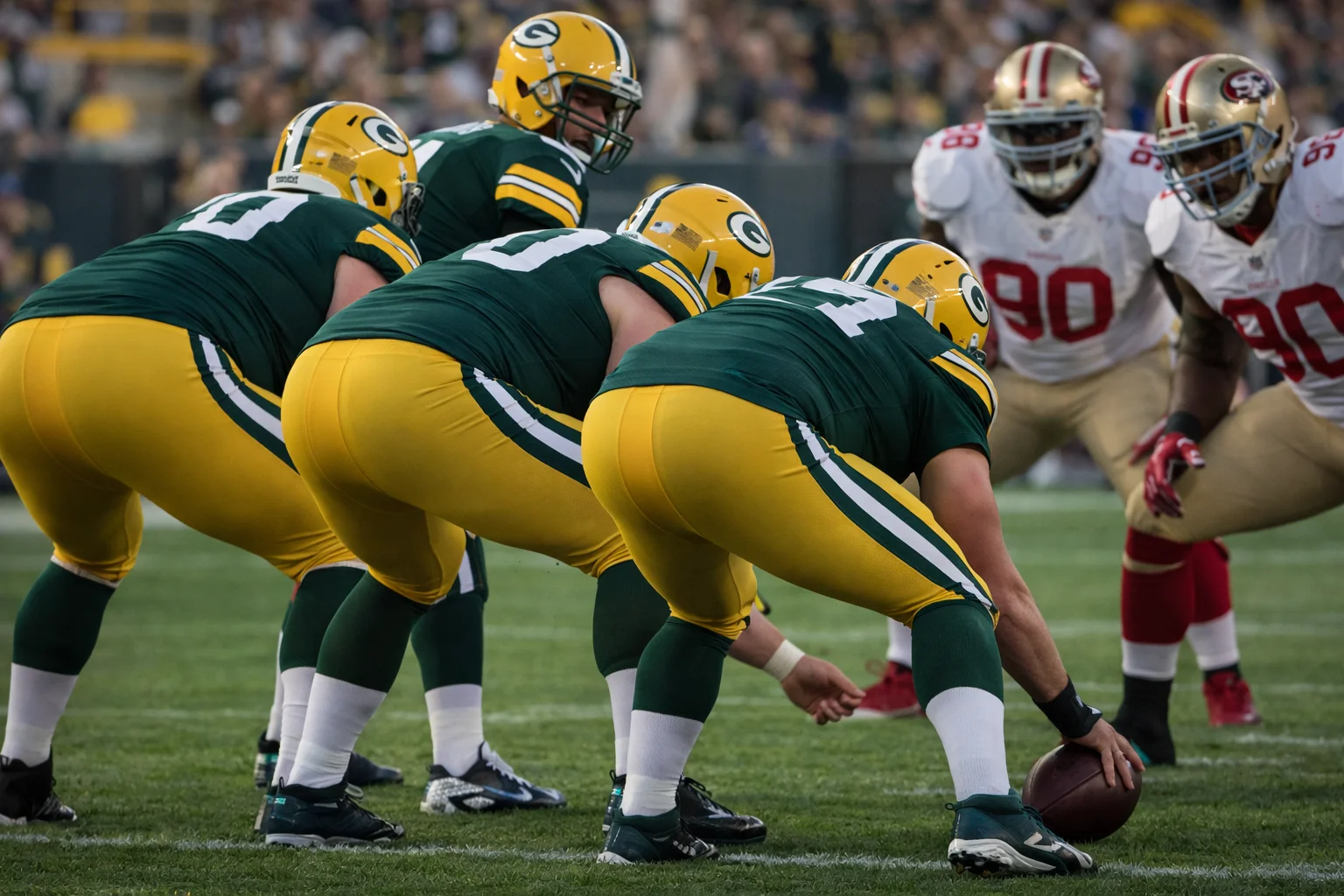 Football players in green jerseys preparing for a play.